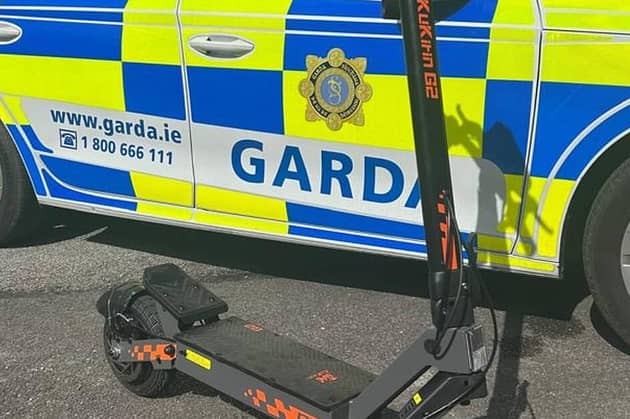 An e-scooter beside a Garda car.