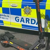An e-scooter beside a Garda car.