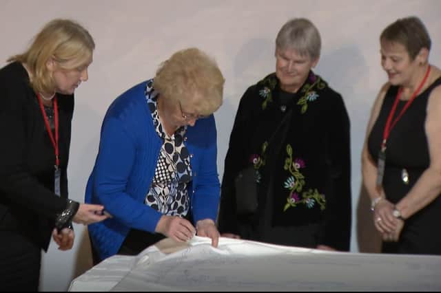 Mary Ging sews the first stitch in the bicentennial memorial piece of Mountmellick embroidery, watched by board members Eliz Moore, Noreen Savage and Janet Stewart, November 2025.